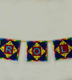 Coloured patchwork squares strung along a wall with name spelled out on centres