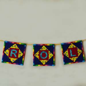 Coloured patchwork squares strung along a wall with name spelled out on centres